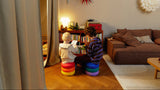 Two children sitting on colorful stools in a cozy living room, reading together.