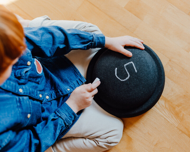 Kid is writing with chalk on Stapelstein Original black